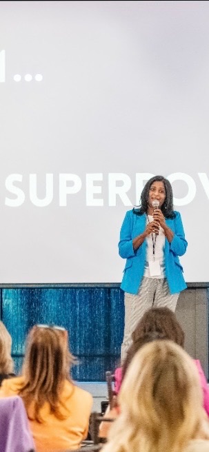 Sapna Rad speaking on stage with a microphone